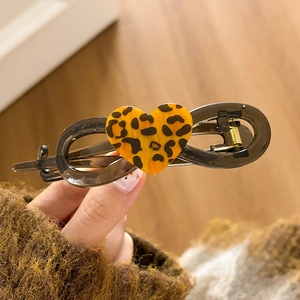 Macro detail of dark grey infinity-shaped hair clip with leopard print heart decoration