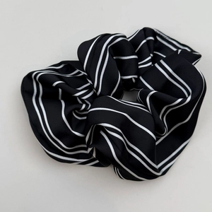 Detail of oversized black and white striped satin scrunchie with smooth pleated texture