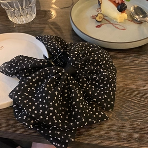 Detailed shot of a French vintage black polka dot mesh bow hair claw clip on wood table