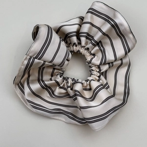Detail of a large silk striped scrunchie with beige and black patterns on white background