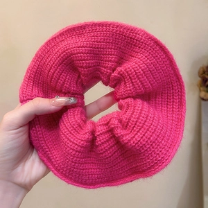 Detailed view of an oversized rose pink chunky knit scrunchie held in hand for size