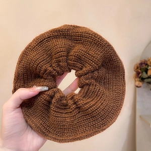 Detail of a large dark brown chunky knit oversized scrunchie with soft wool texture