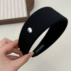 Close-up of black wool wide headband with silver engraved metal buckle and handmade label