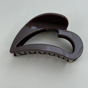 Detail of dark brown heart-shaped hollow hair claw clip with glossy resin finish