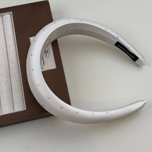 Close-up of handmade cream satin headband with silver rhinestones on a wooden tray