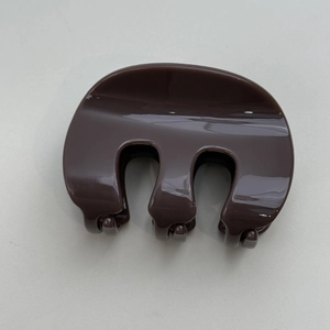 Détail de la pince à cheveux marron en forme de M avec finition brillante et ressort
