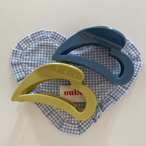 Detail of blue and olive green heart hair claws on a checkered fabric background