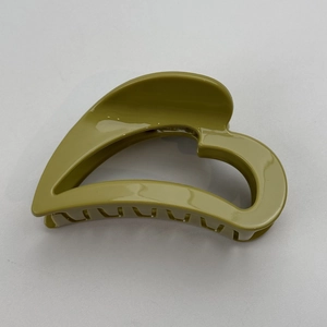 Detail view of heart-shaped olive green hair claw clip with glossy finish and secure grip