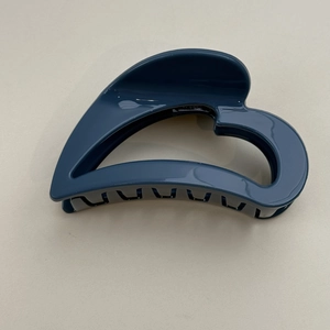 Detail view of large navy blue heart hollow-out hair claw clip with smooth glossy finish