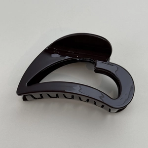 Detail of a large heart-shaped hair claw clip in glossy dark brown resin finish