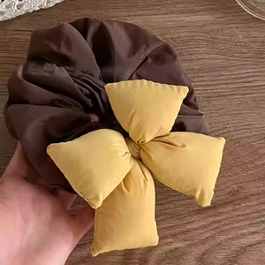 Detailed view of dark brown and ginger yellow fabric scrunchie with large bow design