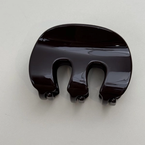 Détail montrant la finition marron brillant et les dents lisses de la pince à cheveux en forme de M