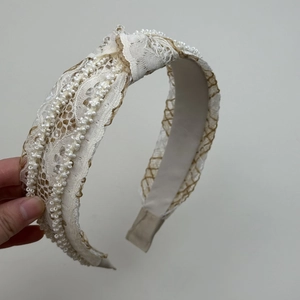 Detail of bohemian wide headband with white lace, pearls, and stylish knot design