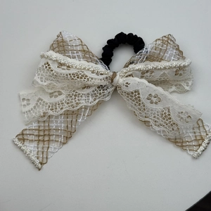 Detail of bohemian bow hair tie featuring white lace, plaid fabric and pearl trim