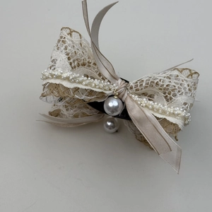 Detail of bohemian beige lace bow hair clip with vintage pearls and floral textures