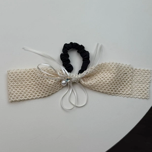 Close-up of woven lace bow hairband with cream pearl and sparkling rhinestone detail
