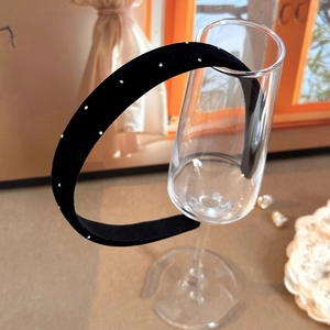 Serre-tête élégant en velours noir avec strass présenté sur un verre transparent