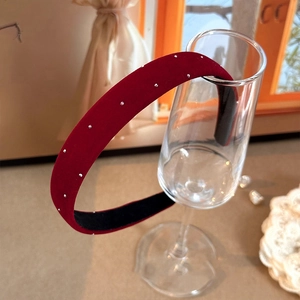 Détail d'un serre-tête en velours bordeaux avec clous argentés sur un verre chic