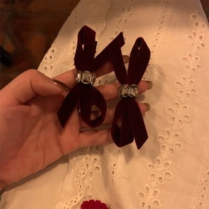 Elegant burgundy velvet bow hair clips with crystal center on a soft white fabric background