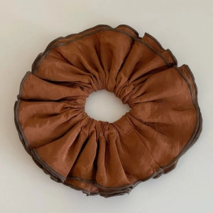 Détail d'un chouchou en satin marron caramel avec des bords de couleur café foncé