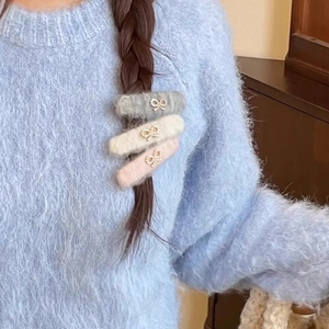 Three plush hair clips in grey, beige and pink with rhinestone bow details worn by a model