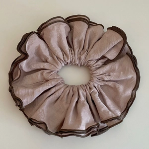 Vue détaillée d'un grand chouchou en satin vieux rose avec bords cousus marron foncé