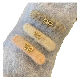 Three plush bow hair clips in grey, beige and pink with sparkling crystal accents