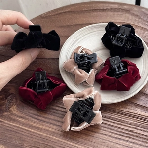 Elegant velvet bow hair clips for women in black, burgundy and beige set on ceramic plate