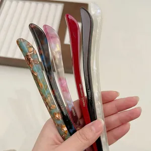 Minimalist acetate hair sticks in multiple elegant colors held for styling demonstration