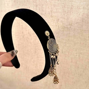 Close-up of black velvet headband with golden ethnic tassel and jhumka bell details