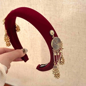 Close-up of wine red velvet headband with golden metallic tassels and small bell pendants