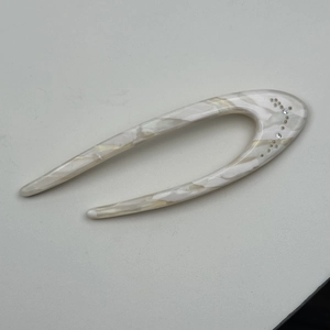 Macro detail of U-shaped acetate hair pin with marble texture and sparkling rhinestones