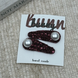 Close-up of handmade wine red sequined hair clips with large white pearls for girls