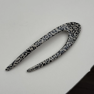 Detailed macro view of U-shaped acetate hair pin with black spots and sparkling crystals