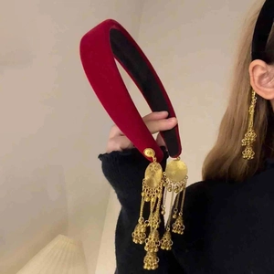Detailed shot of red velvet headband with hanging golden bells and tassel ornaments