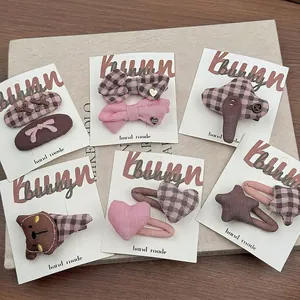 Set di fermagli per capelli in tessuto rosa e marrone con motivi a stella e cuore su carta