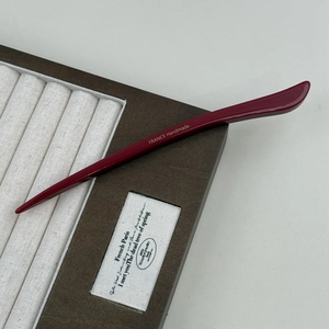 Detail of burgundy acetate hair pin showing the gold France Handmade logo engraving