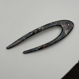 Detail view of U-shaped tortoiseshell hair pin with sparkling rhinestones and metal accents