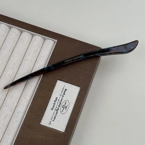 Close-up of elegant acetate hair pin with tortoise pattern and gold handmade logo