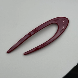 Detailed shot of dark red U-shaped acetate hair pin with sparkling crystal accents