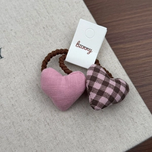 Dettaglio degli elastici per capelli a cuore in tessuto rosa e scozzese su carta