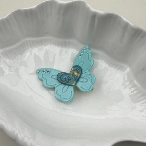 Détail de la pince à cheveux papillon bleu clair avec cœur et strass scintillants