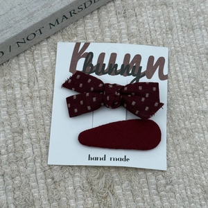 Detail of red polka dot bow hair clip and droplet hairpin set on textured background