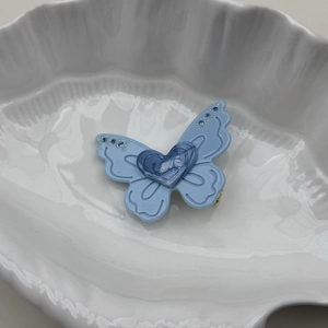 Détail de la pince à cheveux papillon bleu clair avec cœur LOVE et strass étincelants