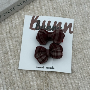 Detail of two handmade red plaid fabric bow hair clips set on a white bunny display card