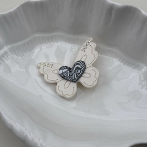 Détail d'une pince à cheveux papillon avec gravure LOVE en cœur et strass brillants