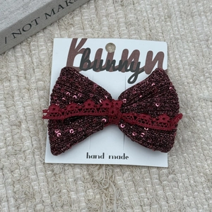 Close-up of sparkling dark red bow hair clip with lace detail on bunny card