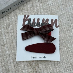 Deep red bow and oval hair clip set for girls on a cream fabric background