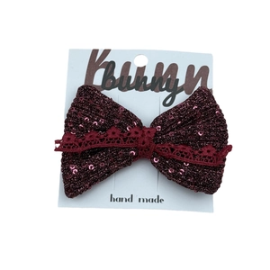 Handmade red sequin bow hair clip with lace detail for girls on a white display card