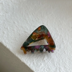 Close-up of a handmade tortoise shell acetate triangle hair claw on a white textured background